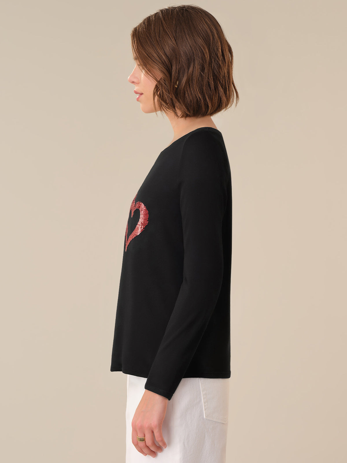 Person wearing a black sweater with a red heart design on a beige background