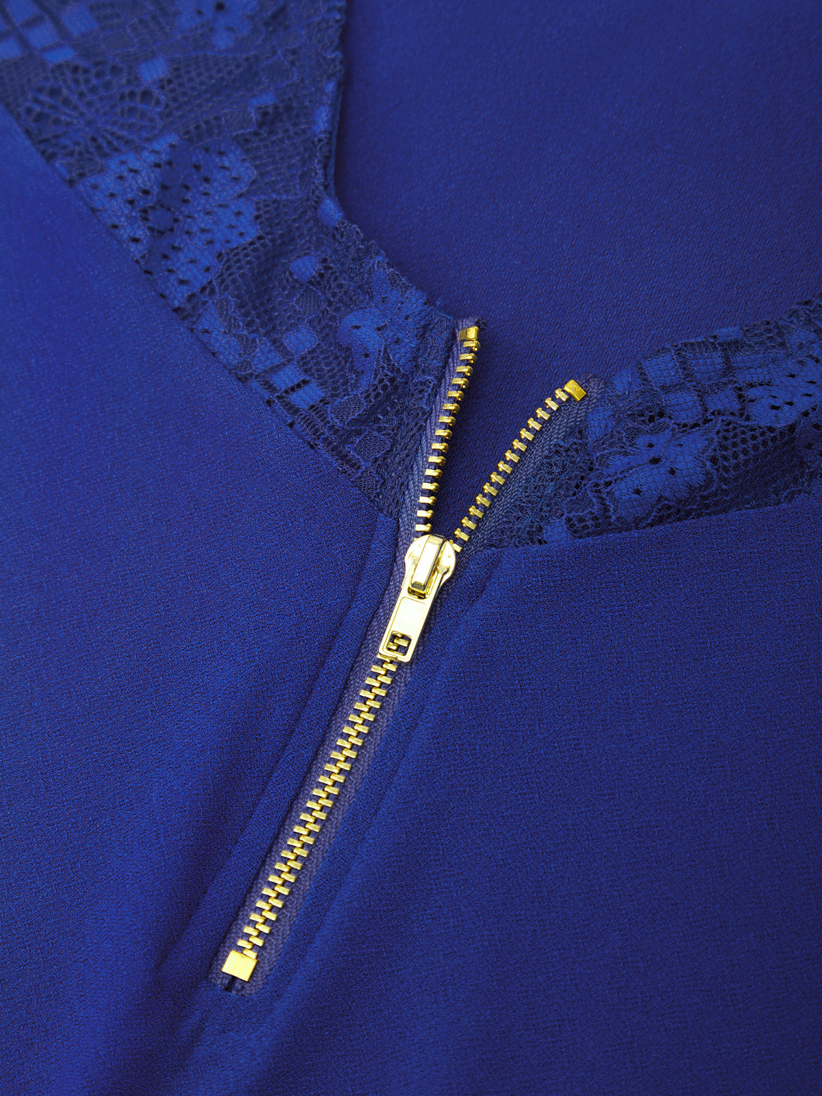 Close-up of a royal blue garment featuring a gold zipper and dark blue lace trim at the neckline.