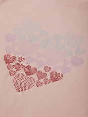 Pink sweatshirt with decorative heart patterns made of small stones on a light pink background