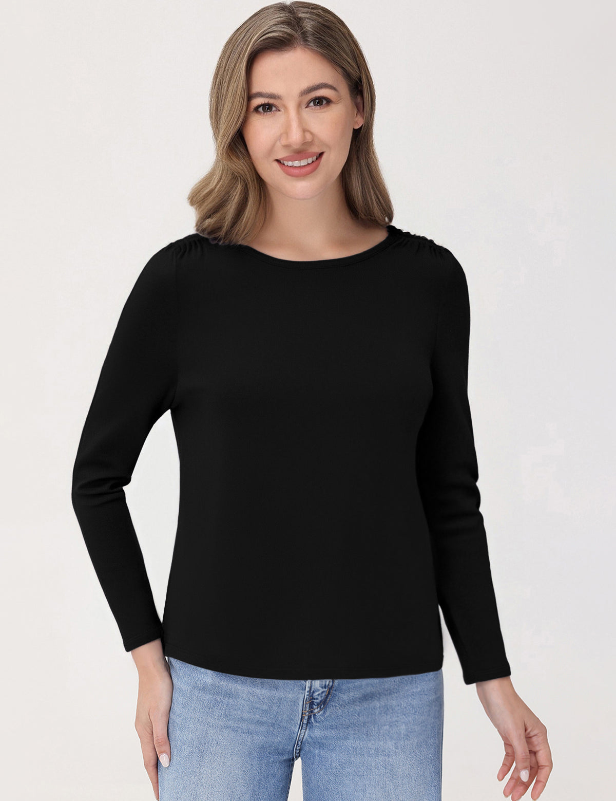 Woman wearing a black long-sleeve top and blue jeans on a white background