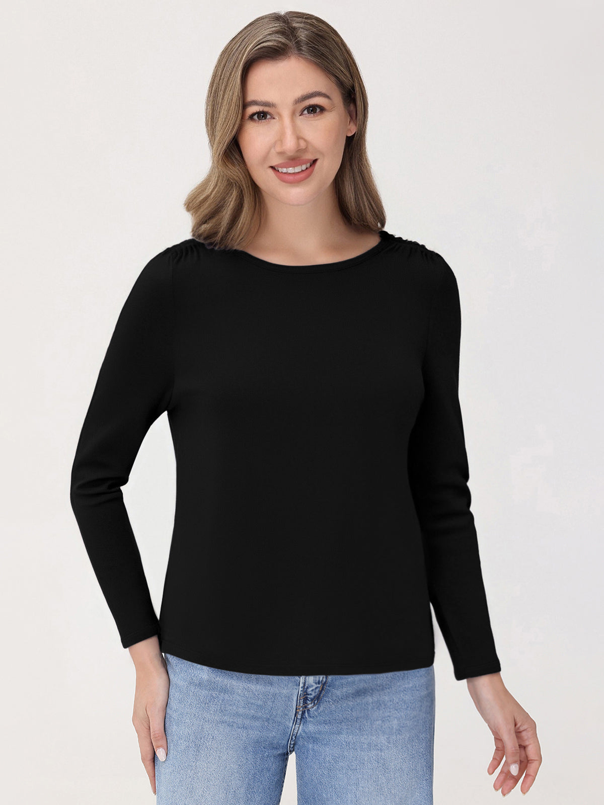 Woman wearing a black long-sleeve top and blue jeans on a white background