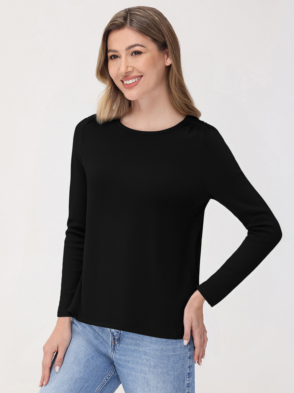 Woman wearing a black long-sleeve top and blue jeans on a white background