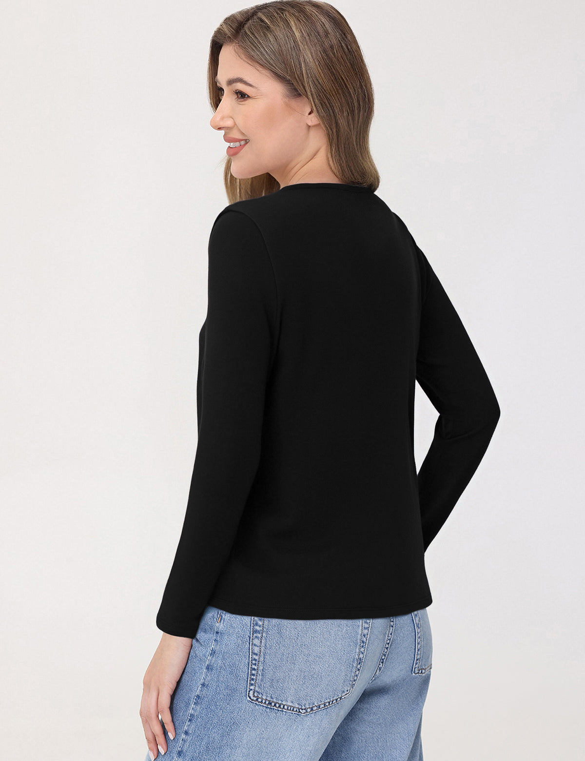 Woman wearing a black top and light blue jeans on a white background