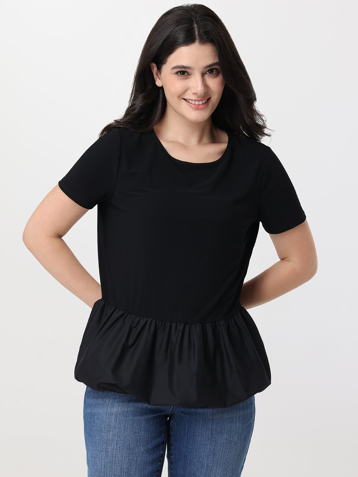 Woman wearing a black peplum top and blue jeans on a white background