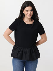 Woman wearing a black peplum top and blue jeans on a white background