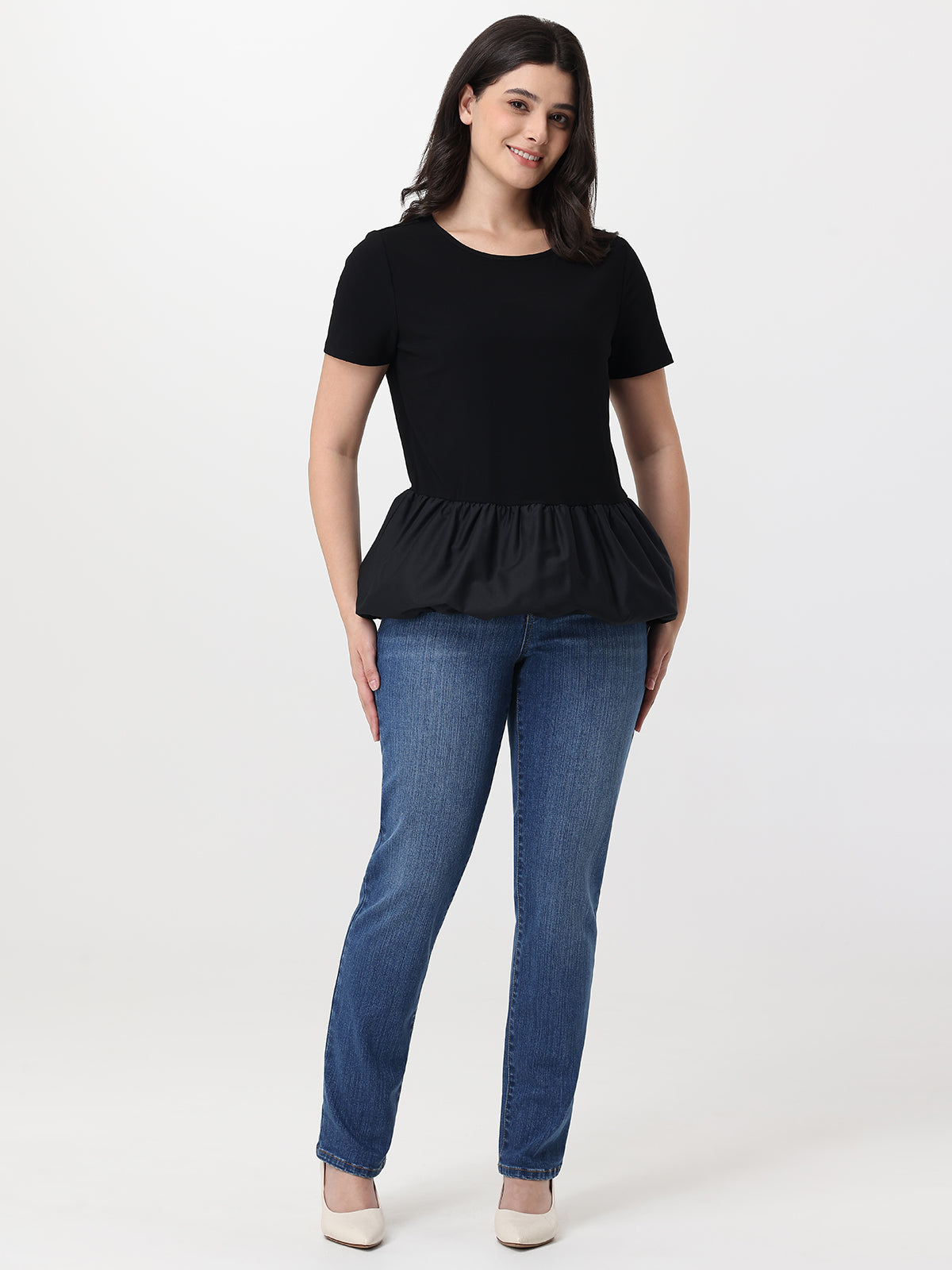 Woman wearing a black peplum top and blue jeans on a white background
