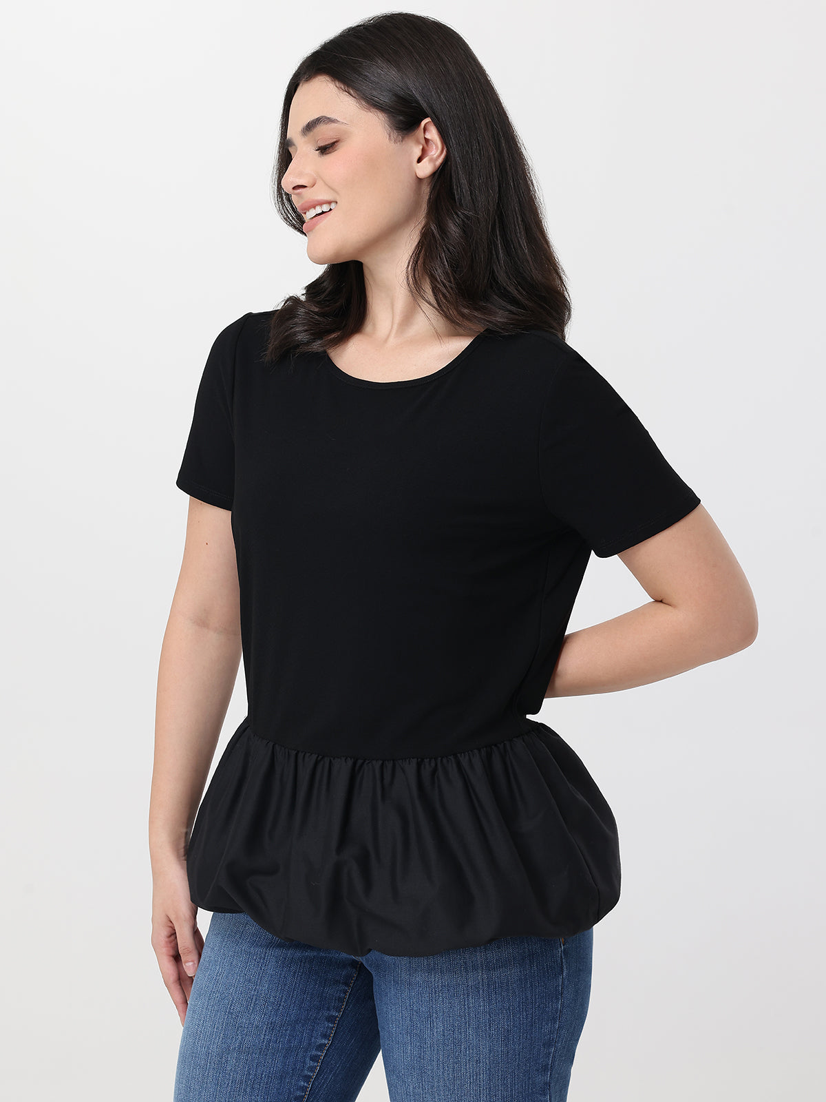 Woman wearing a black peplum top and blue jeans on a white background