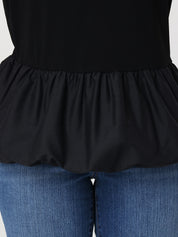 Black peplum top worn over blue jeans on a plain background