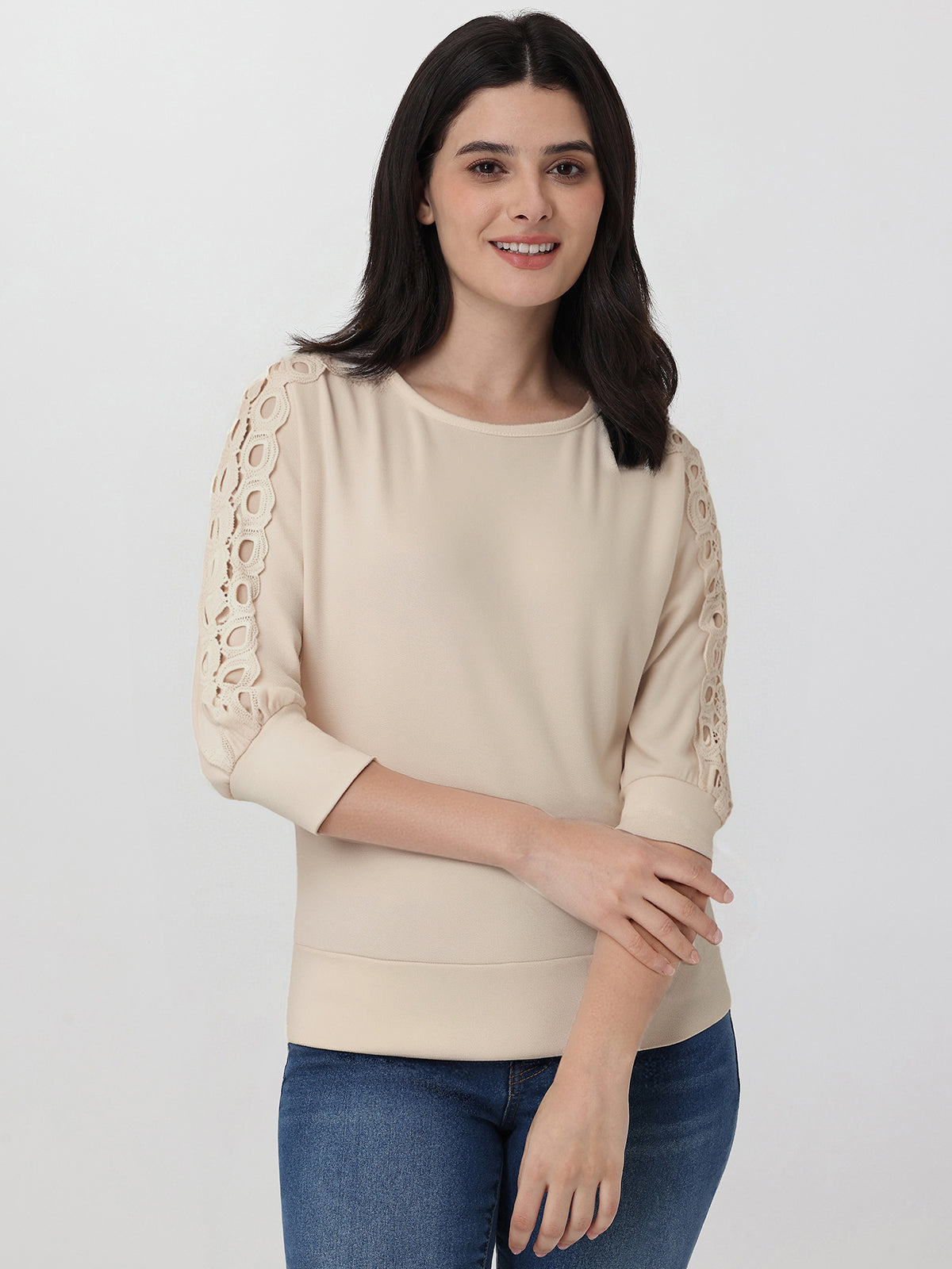 Woman wearing a beige sweater with lace sleeves on a white background