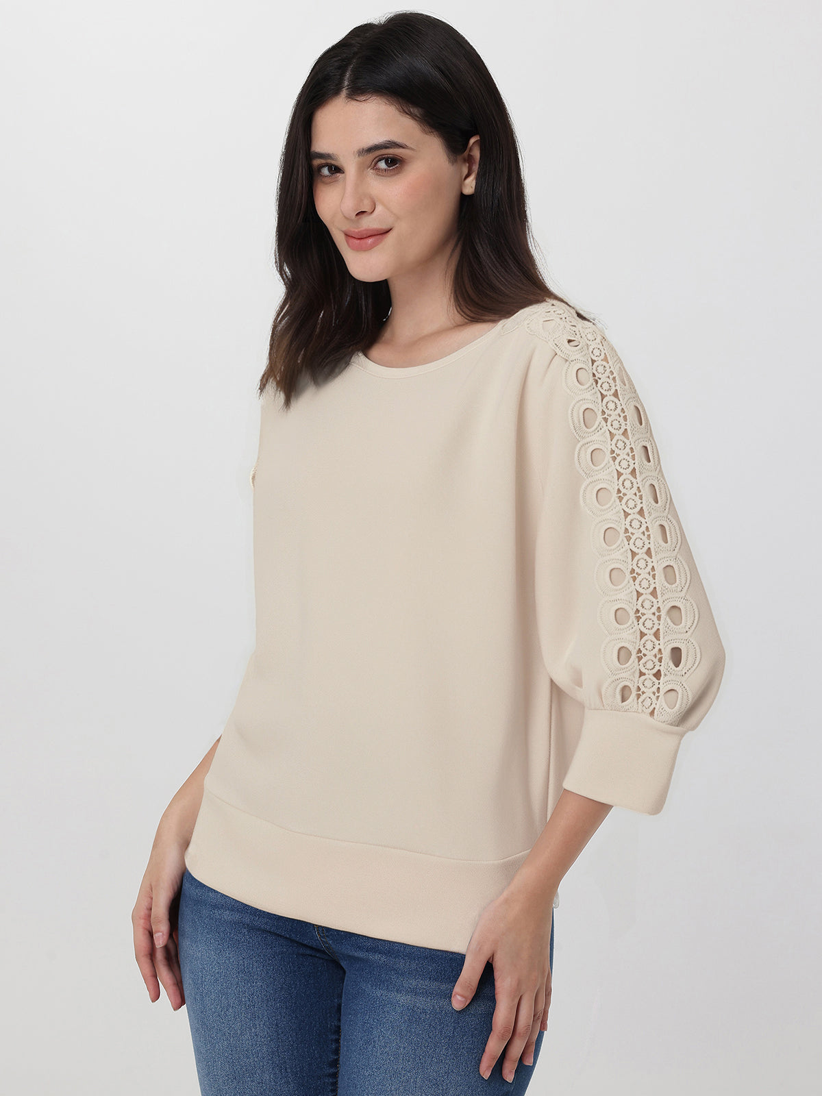 Woman wearing a beige sweater with lace sleeves on a white background