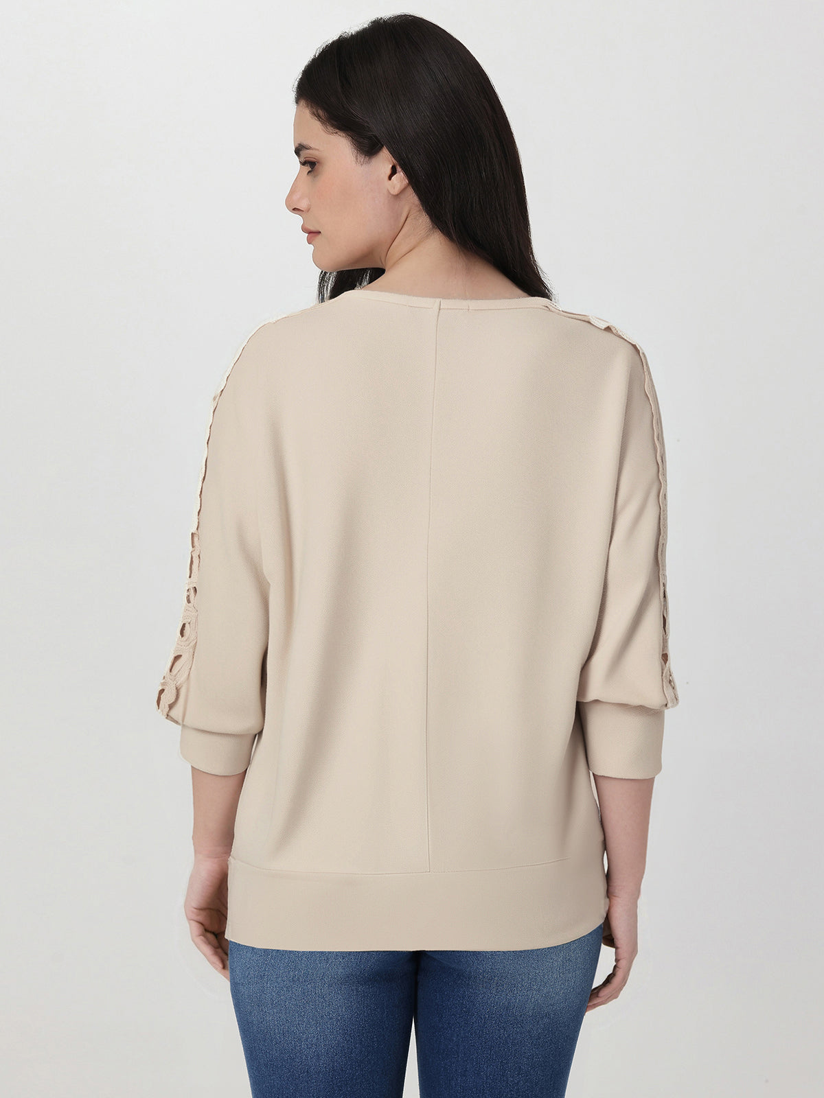 Woman wearing a beige sweater with rolled-up sleeves on a white background