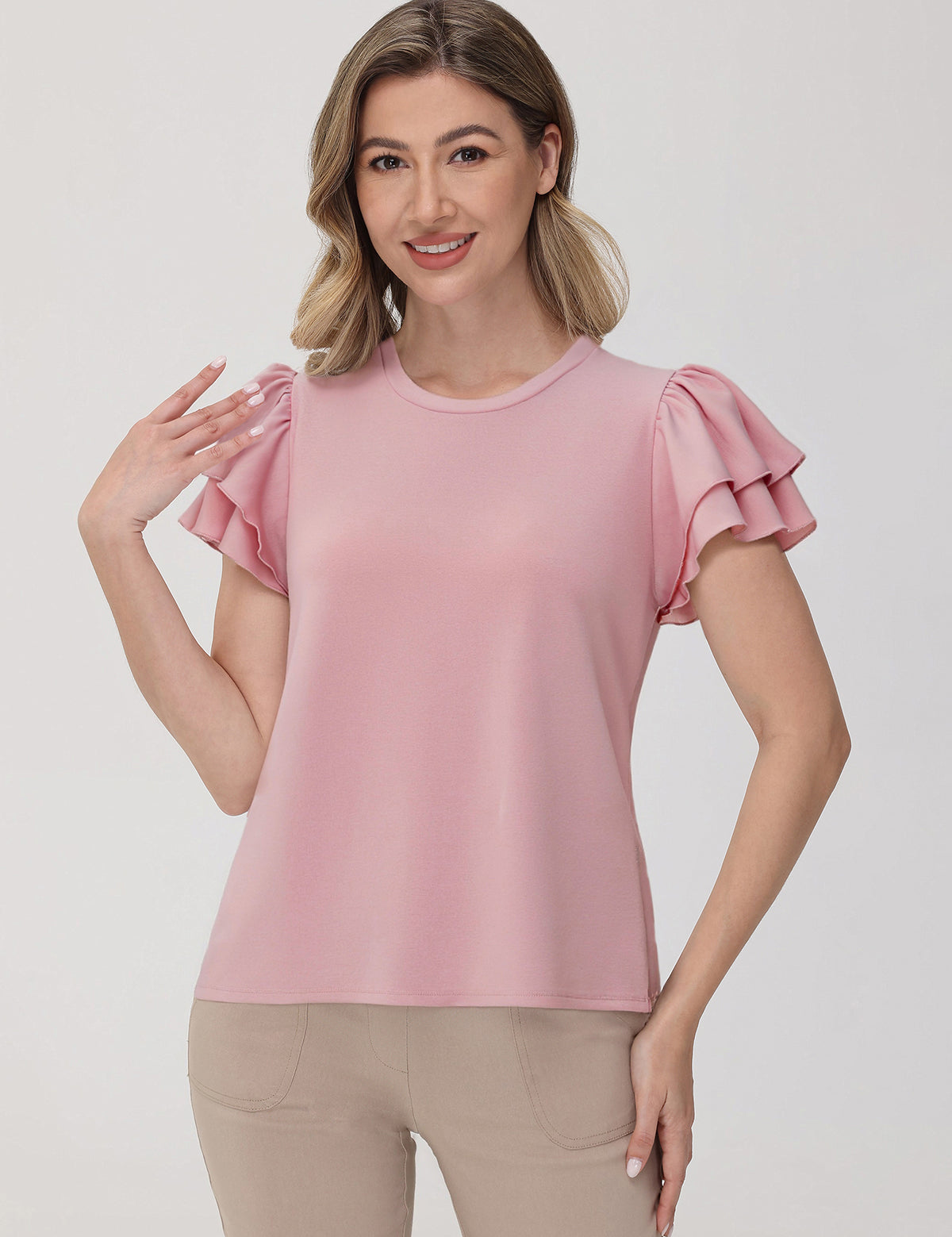 Woman wearing a pink blouse with ruffled sleeves on a plain background