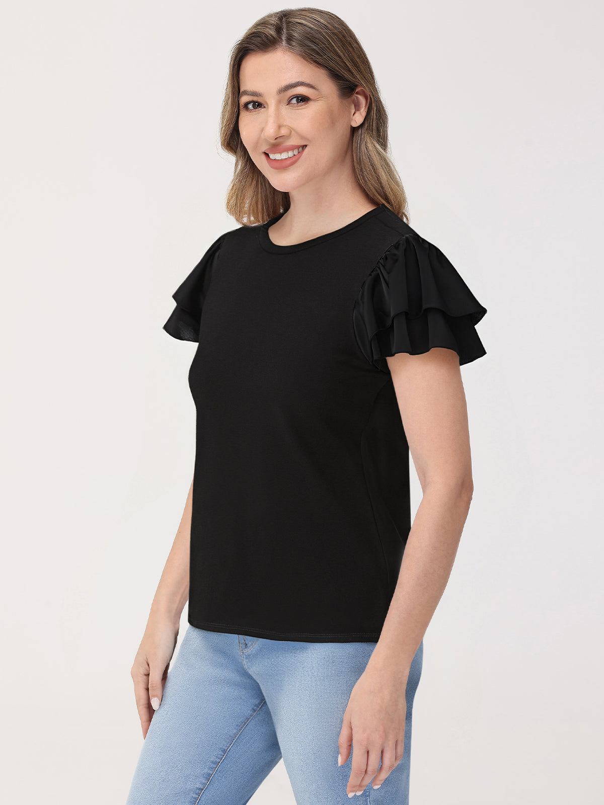 Woman wearing a black ruffled sleeve top against a white background