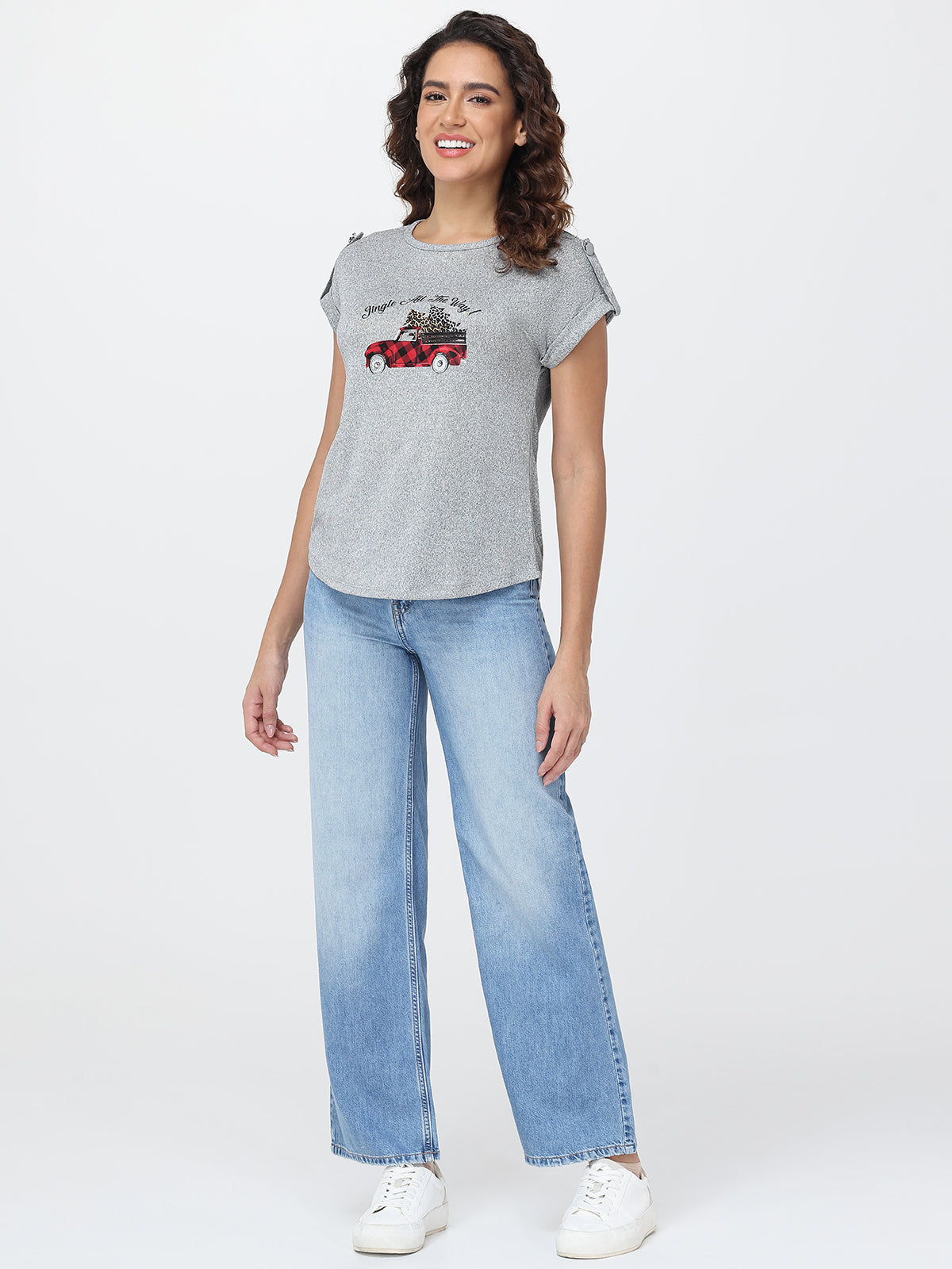 Woman wearing a gray t-shirt with a graphic design and blue jeans on a white background