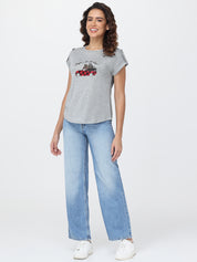 Woman wearing a gray t-shirt with a graphic design and blue jeans on a white background