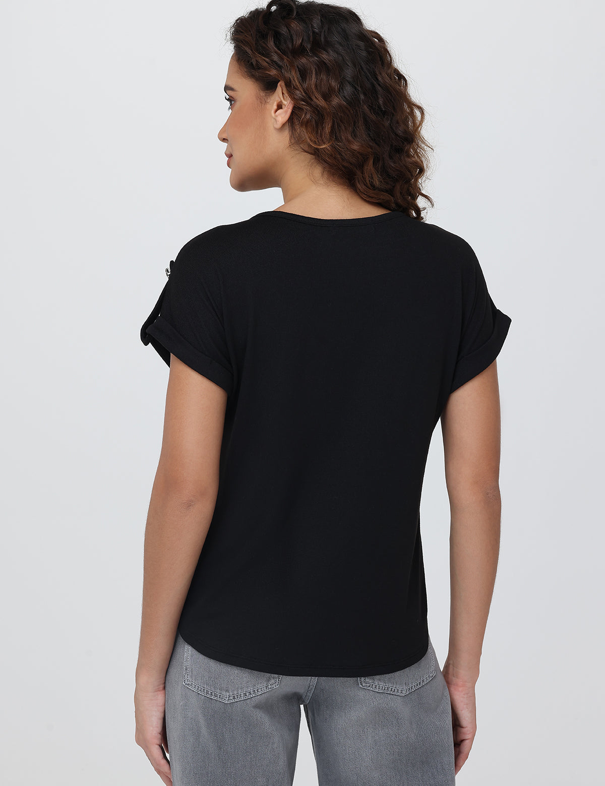 Woman wearing a black t-shirt and gray pants on a white background