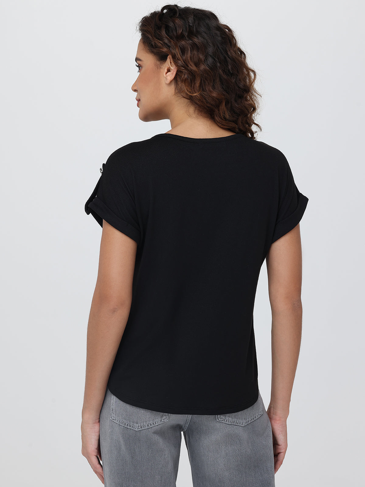 Woman wearing a black t-shirt and gray pants on a white background