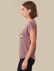 Woman wearing a purple t-shirt with a colorful design on a beige background