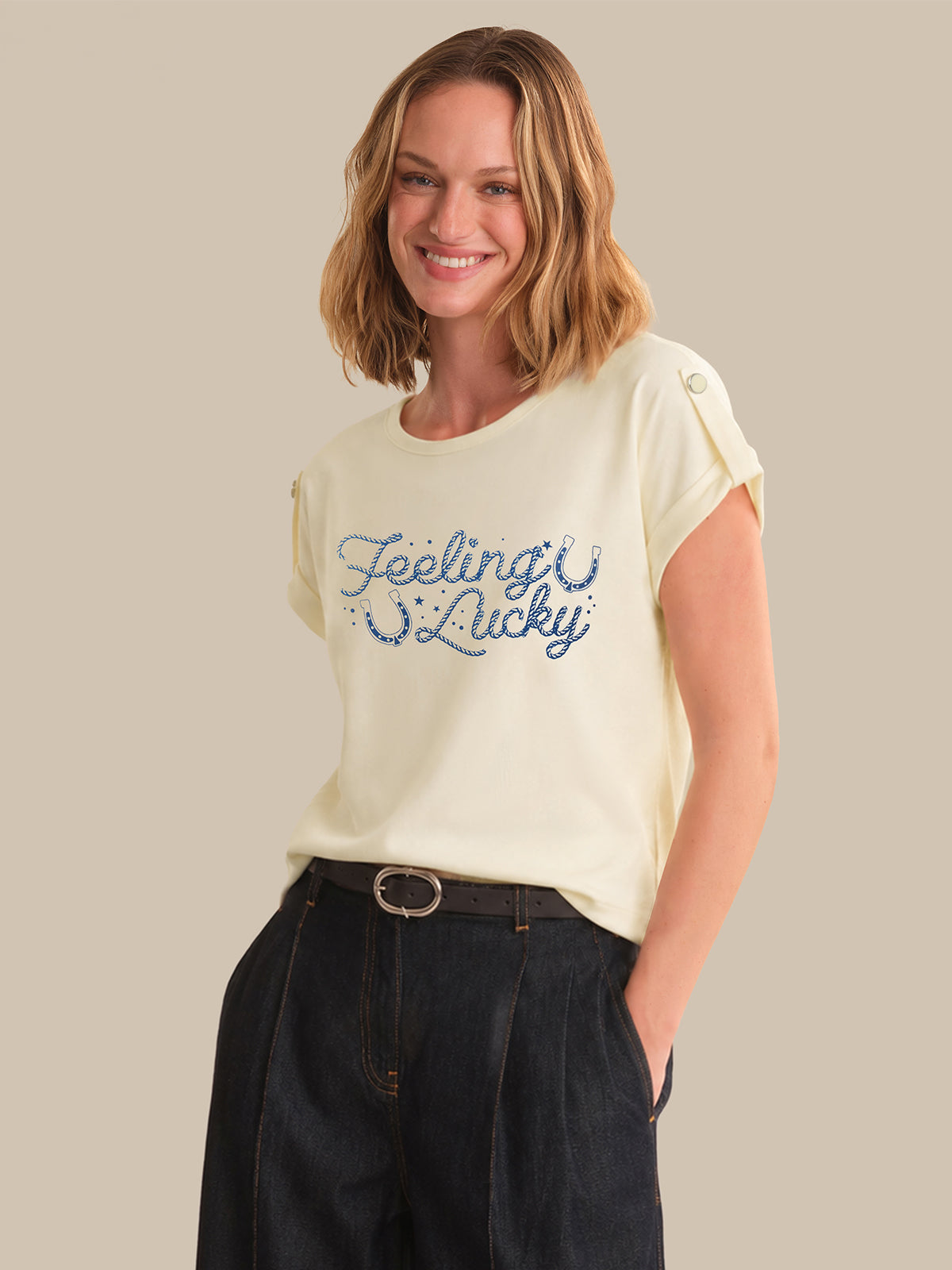 Woman wearing a cream t-shirt with 'Feeling Lucky' text on a beige background