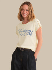 Woman wearing a cream t-shirt with 'Feeling Lucky' text on a beige background