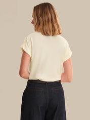 Person wearing a light-colored top and dark jeans on a beige background