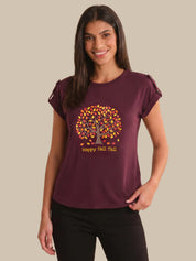 Woman wearing a maroon t-shirt with a tree design and 'Happy Fall Yall' text on a beige background