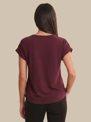 Woman wearing a maroon t-shirt against a beige background