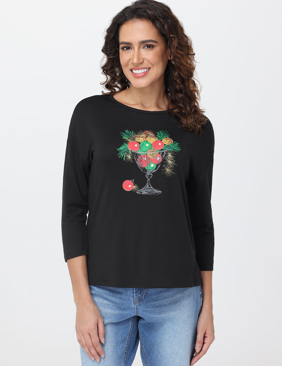 Woman wearing a black long-sleeve shirt with a glass design featuring fruits and flowers on a white background.
