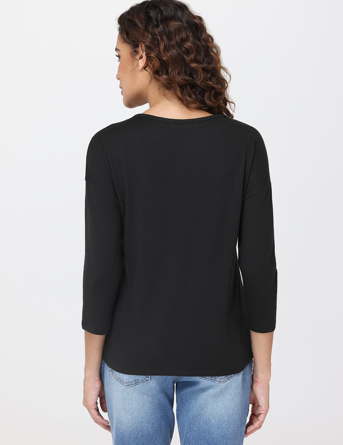 Person wearing a black long-sleeve top and blue jeans on a white background