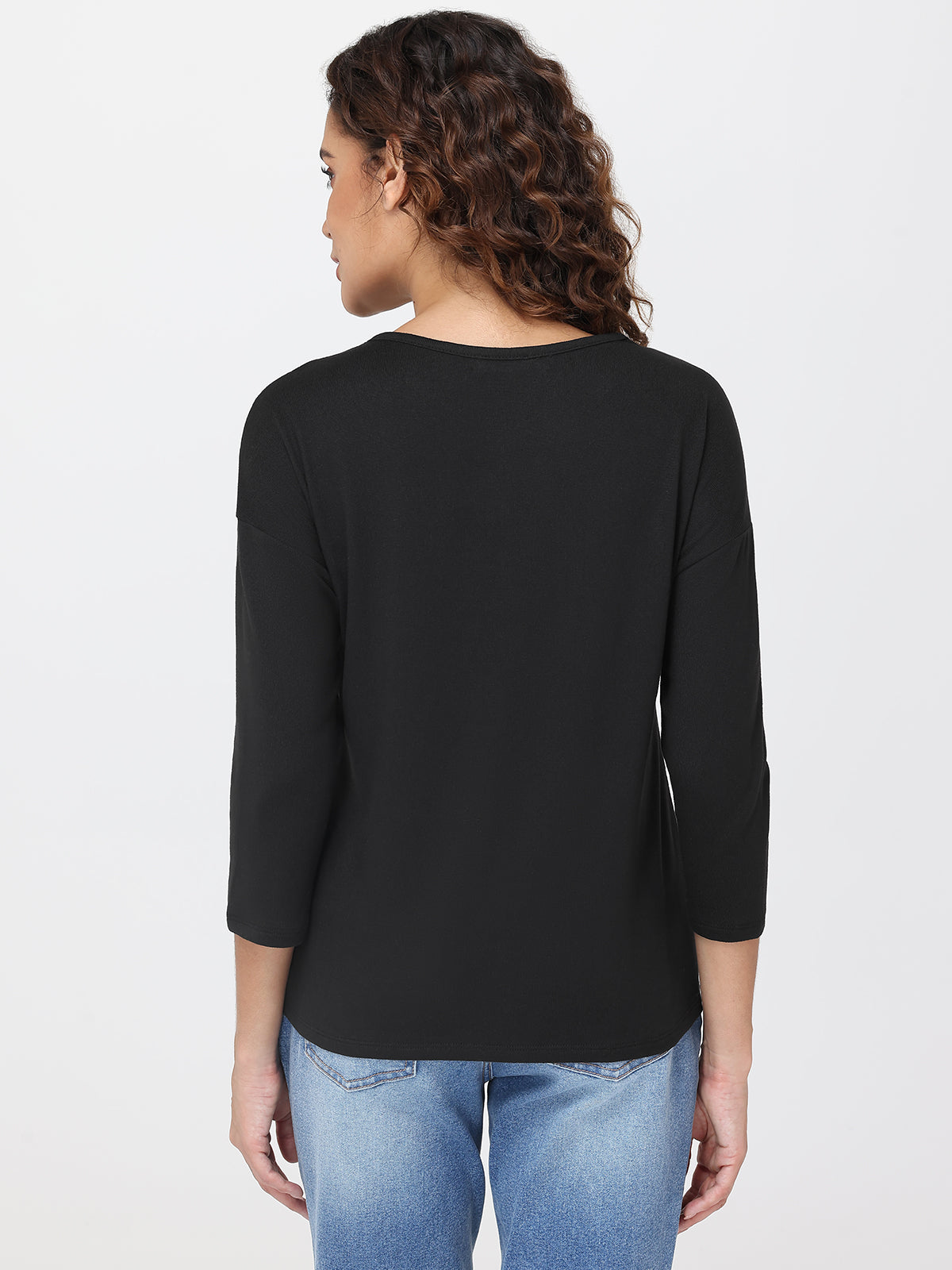 Person wearing a black long-sleeve top and blue jeans on a white background