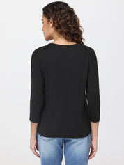 Person wearing a black long-sleeve top and blue jeans on a white background