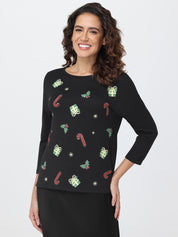 Woman wearing a black top with Christmas-themed patterns on a white background
