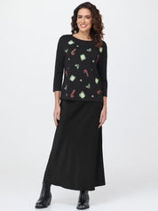 Woman wearing a black top with colorful patterns and a black skirt on a white background