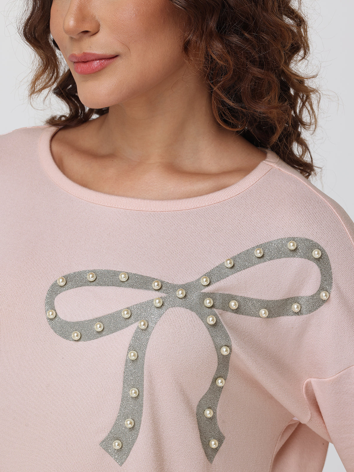 Pink tops with a decorative bow design on a plain background