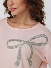 Pink tops with a decorative bow design on a plain background