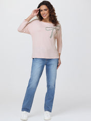 Woman wearing a light pink top with a decorative element and blue jeans on a white background