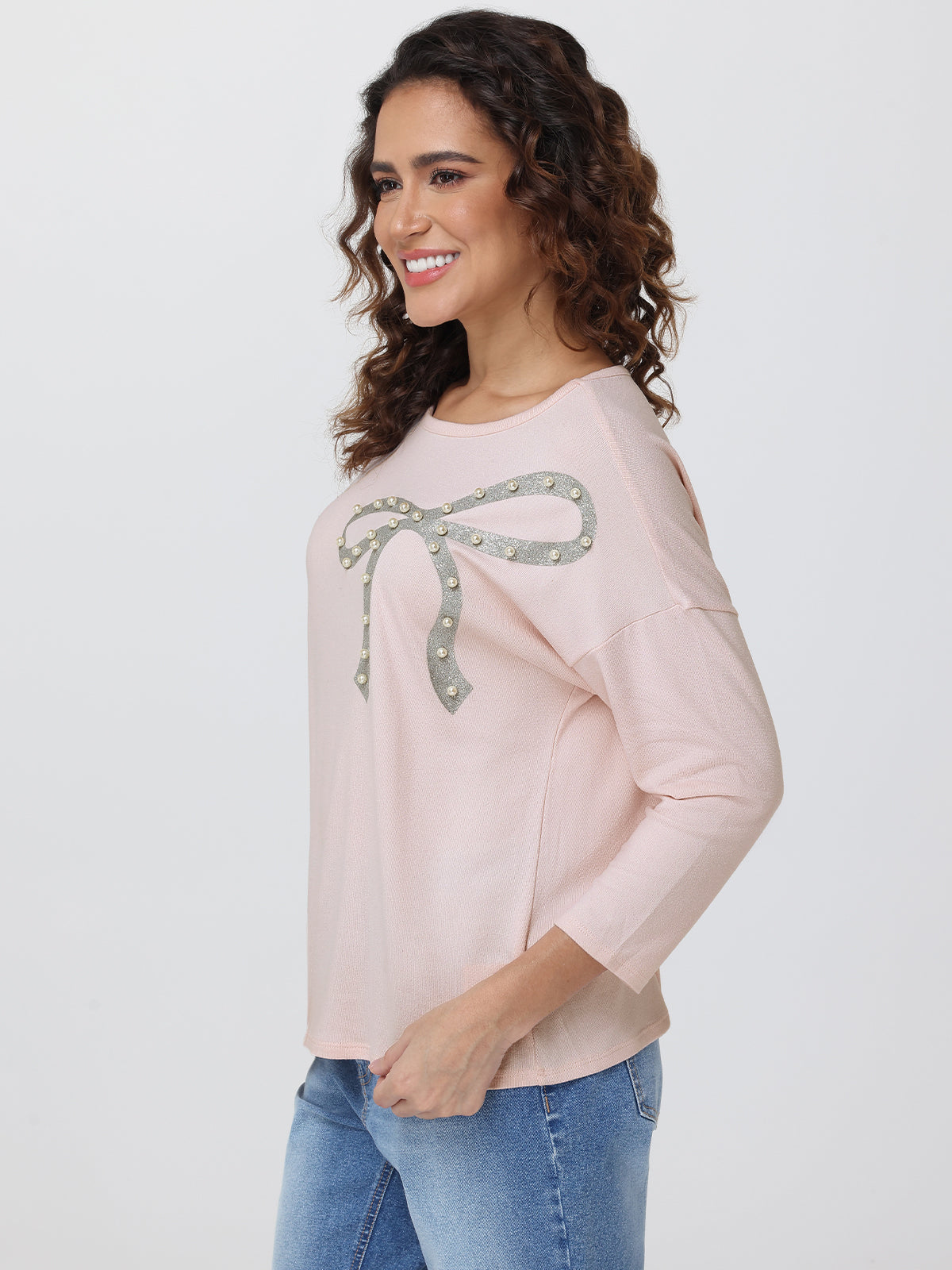 Woman wearing a light pink sweater with a decorative bow design on a white background