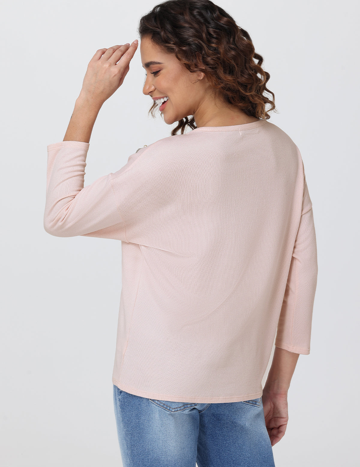 Woman wearing a light pink blouse and blue jeans on a white background