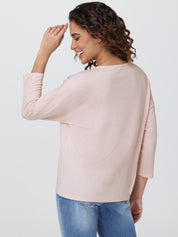 Woman wearing a light pink blouse and blue jeans on a white background