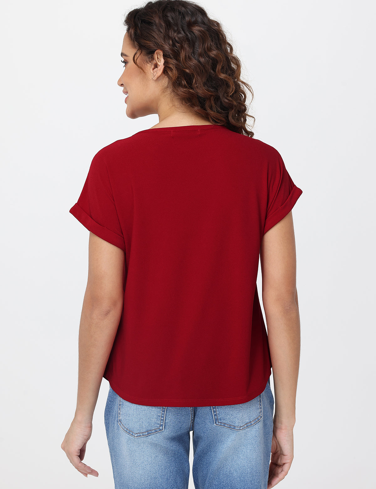 Woman wearing a red t-shirt and blue jeans on a white background