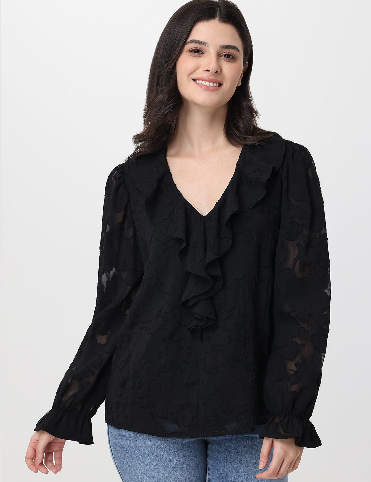 Woman wearing a black blouse with ruffled details on a white background