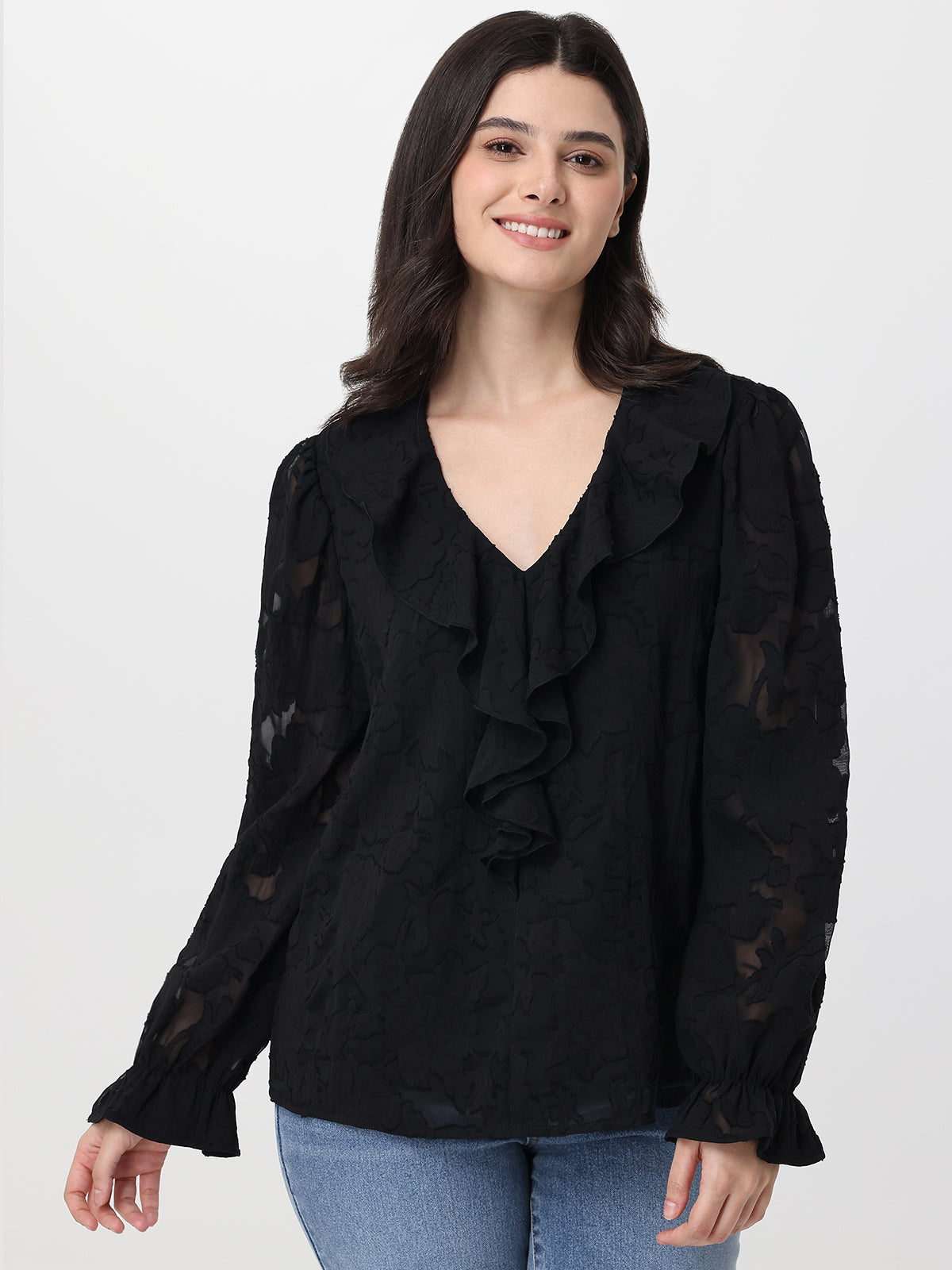 Woman wearing a black blouse with ruffled details on a white background