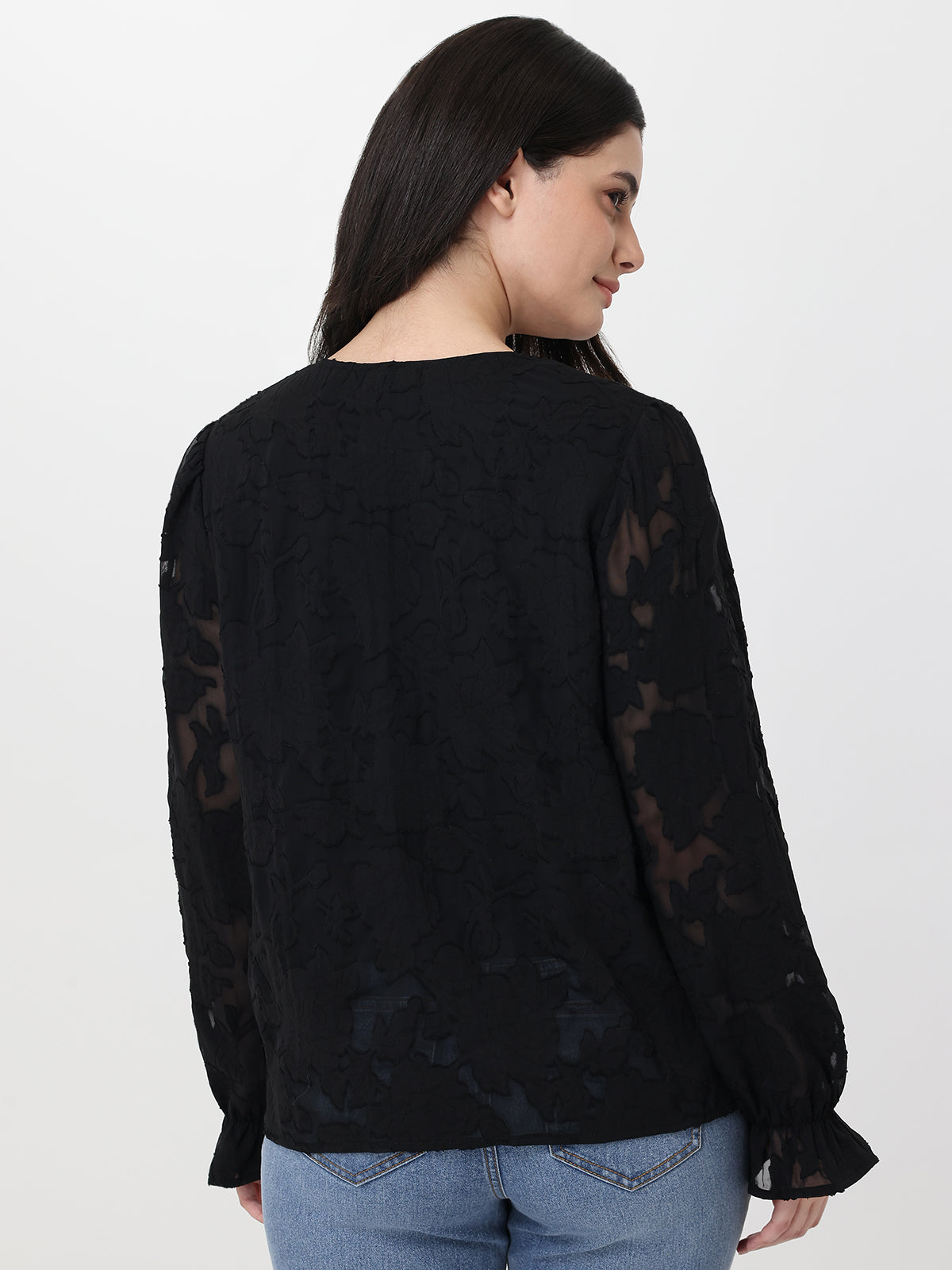 Woman wearing a black lace top with sheer sleeves on a white background