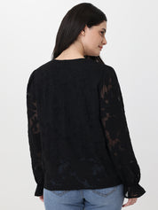 Woman wearing a black lace top with sheer sleeves on a white background