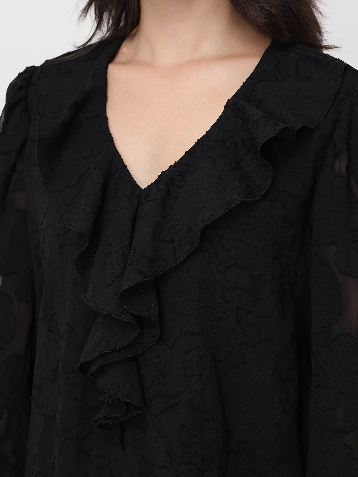 Close-up of a black textured blouse with ruffled details.
