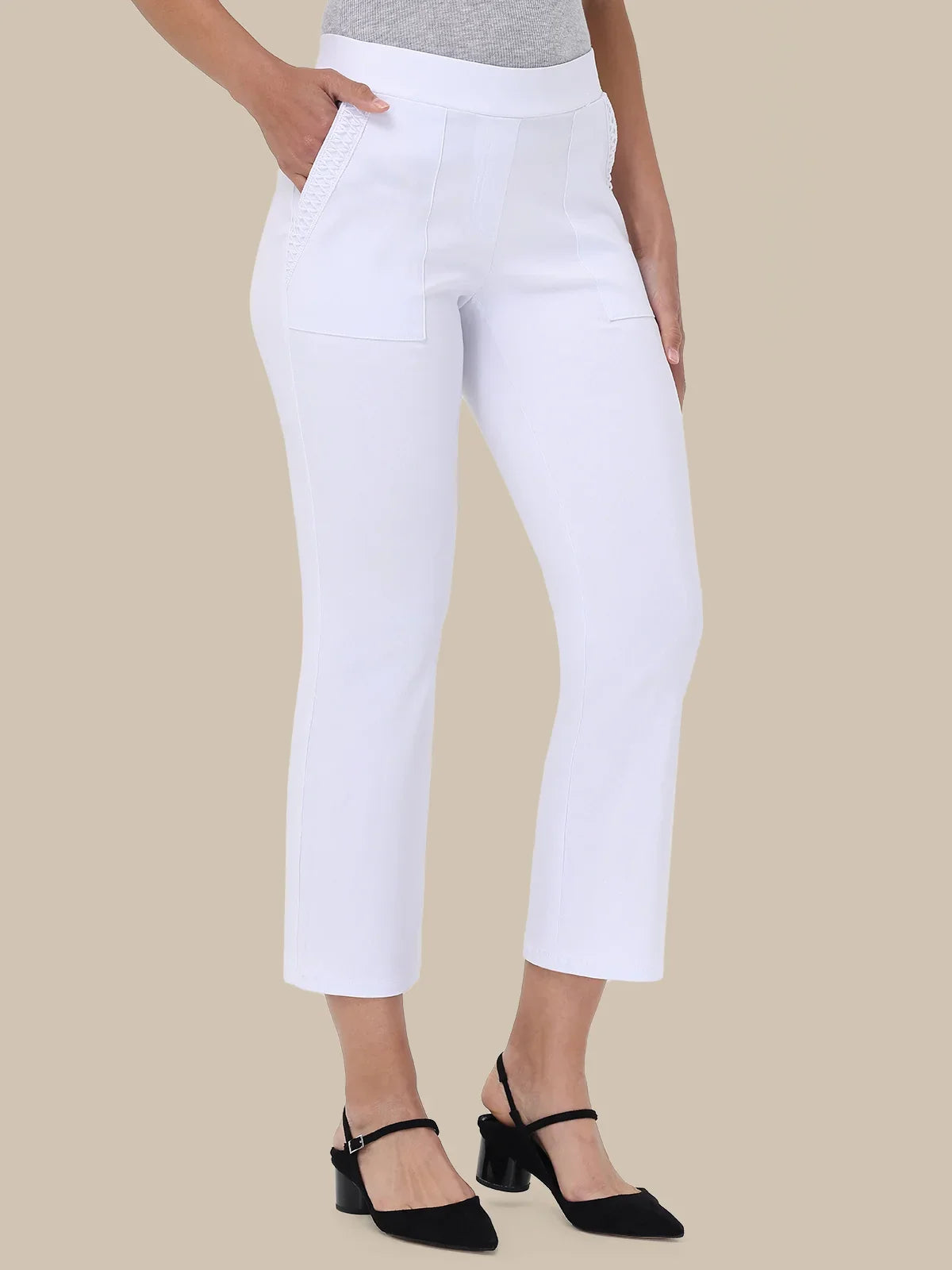 White cropped ankle-length pants with front patch pockets, shown on a model wearing a gray top and black heeled sandals against a beige studio background.