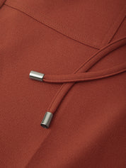 Close-up of a rust-colored hood with drawstrings on a matching fabric background