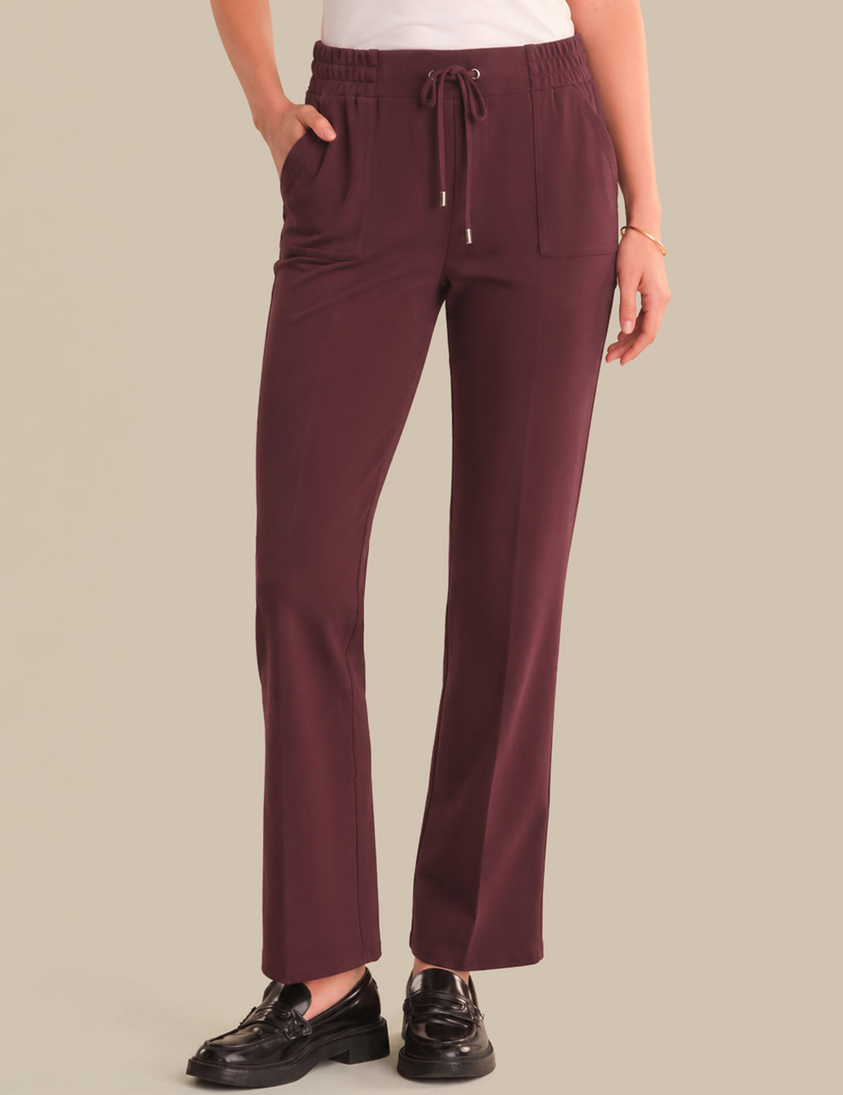 Maroon pants worn by a person on a beige background