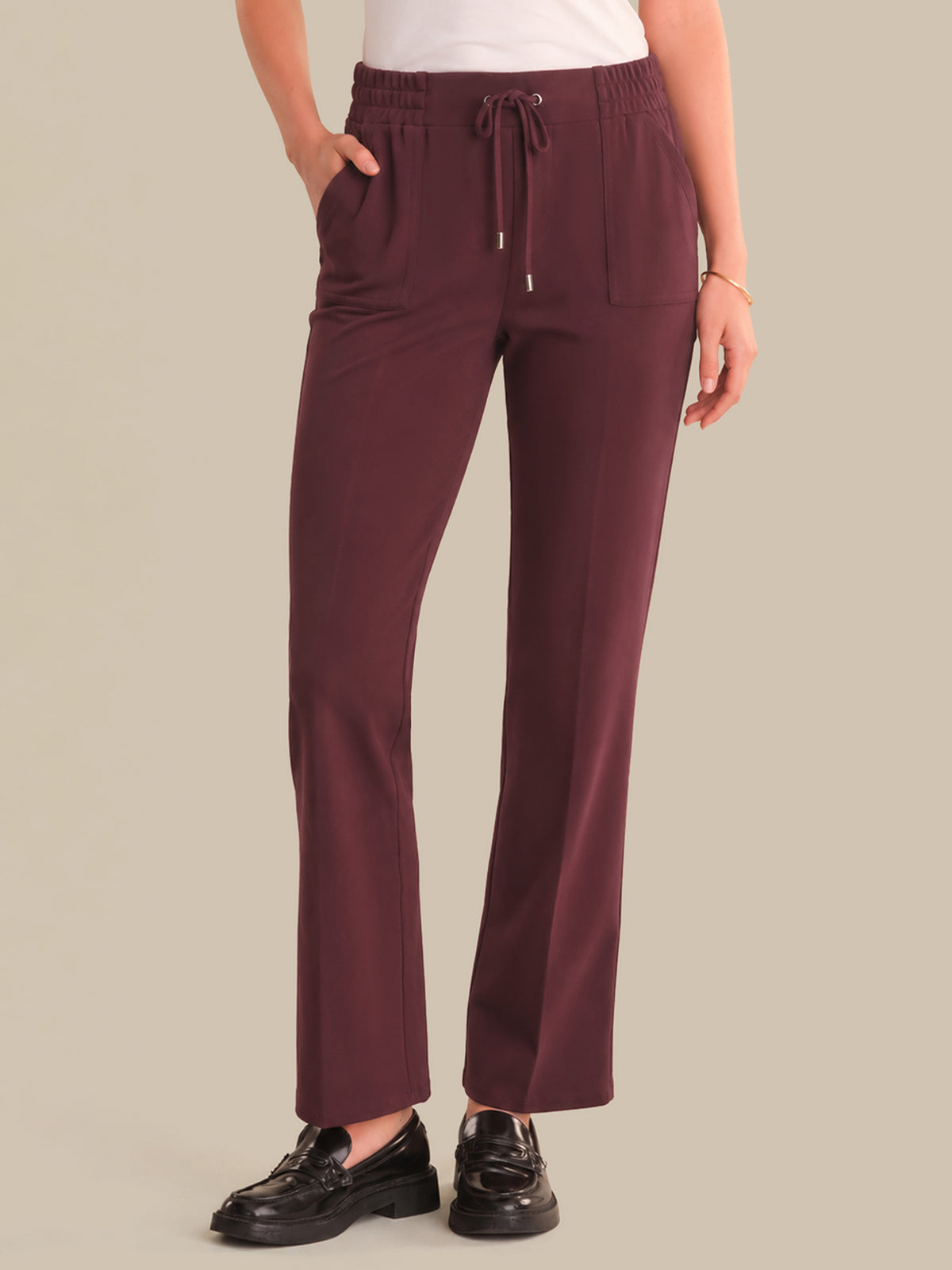 Maroon pants worn by a person on a beige background