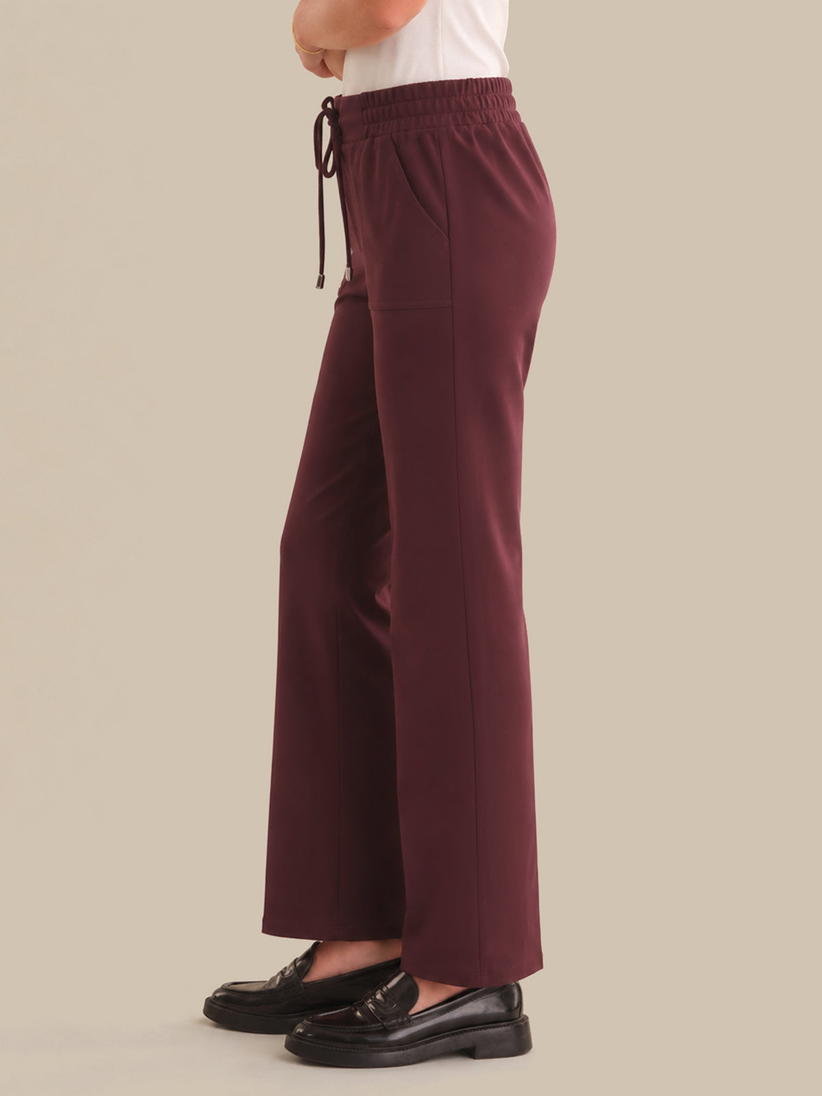 Maroon pants worn by a person on a beige background